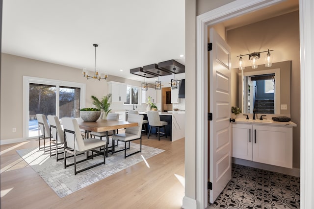 dining space with light wood-style floors, recessed lighting, a healthy amount of sunlight, and an inviting chandelier