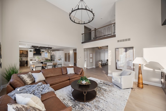 living area featuring light wood-type flooring, an inviting chandelier, baseboards, and visible vents