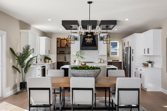 kitchen featuring stainless steel appliances, a kitchen island, white cabinetry, light countertops, and pendant lighting