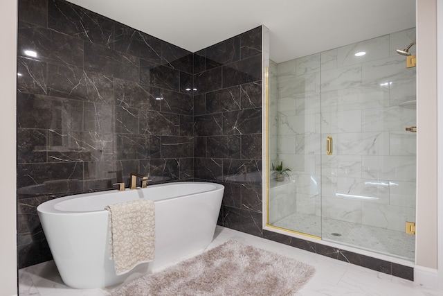 full bathroom featuring tile walls, marble finish floor, a freestanding tub, and a shower stall