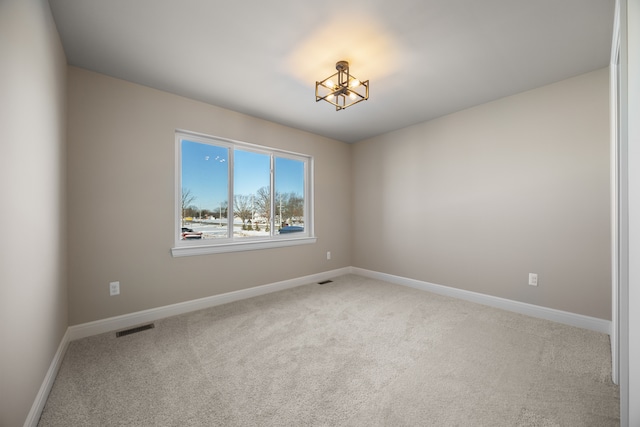 unfurnished room with carpet floors, visible vents, and baseboards