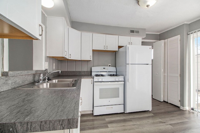 kitchen with white appliances, sink, hardwood / wood-style floors, and white cabinets