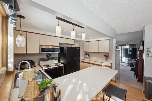 kitchen with electric stove, sink, black fridge, and decorative light fixtures