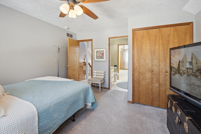 bedroom featuring a textured ceiling, ceiling fan, a closet, and light colored carpet