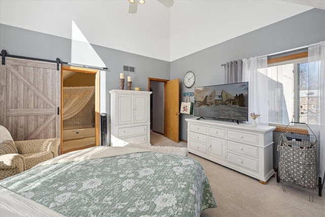 bedroom with a high ceiling, light carpet, ceiling fan, and a barn door