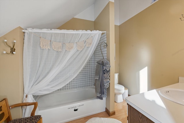 bathroom with toilet, a washtub, vaulted ceiling, hardwood / wood-style floors, and vanity