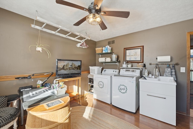 clothes washing area with hardwood / wood-style flooring, ceiling fan, sink, and separate washer and dryer