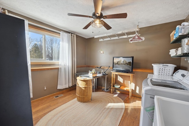 interior space featuring hardwood / wood-style flooring, ceiling fan, a textured ceiling, and washing machine and clothes dryer