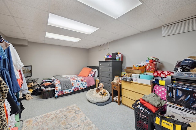 carpeted bedroom featuring a drop ceiling