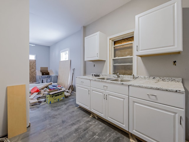 kitchen with wood-type flooring, sink, white cabinets, and light stone counters