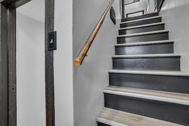 stairway featuring a textured ceiling