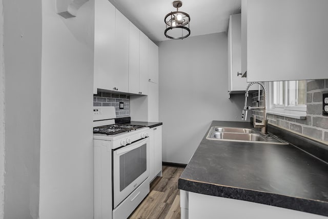 kitchen featuring sink, white gas range oven, white cabinetry, backsplash, and dark hardwood / wood-style floors