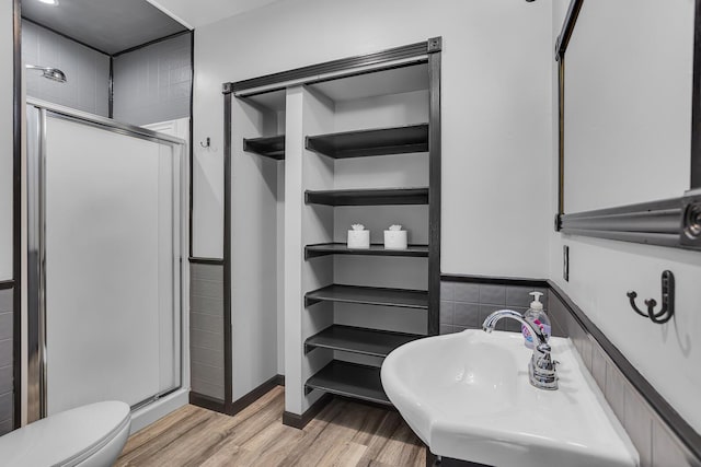 bathroom featuring a shower with door, sink, hardwood / wood-style floors, and toilet