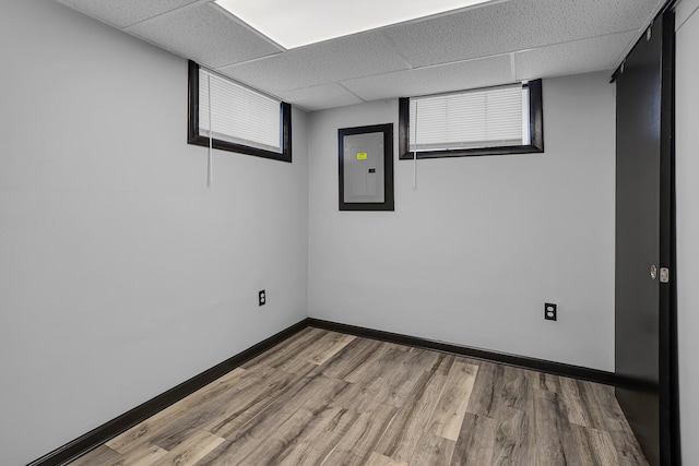 unfurnished room featuring wood-type flooring, electric panel, and a paneled ceiling