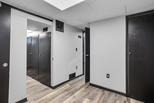 unfurnished bedroom with a closet, light hardwood / wood-style flooring, and a drop ceiling