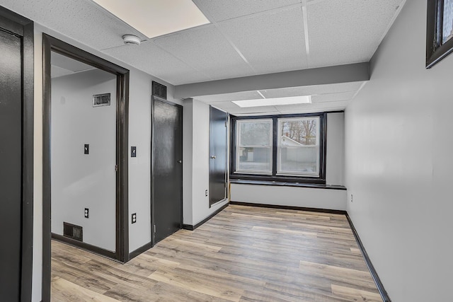 corridor featuring a paneled ceiling and light hardwood / wood-style floors