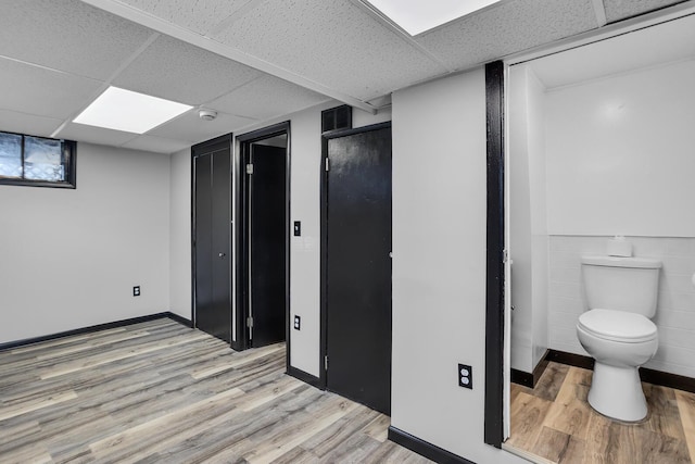 basement with a drop ceiling and light wood-type flooring