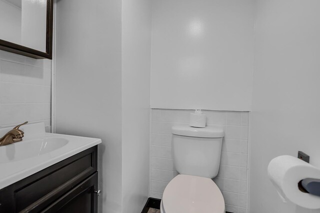 bathroom featuring vanity, tile walls, and toilet