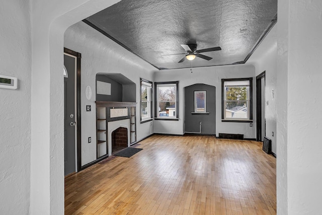 unfurnished living room with plenty of natural light, light hardwood / wood-style floors, and a textured ceiling