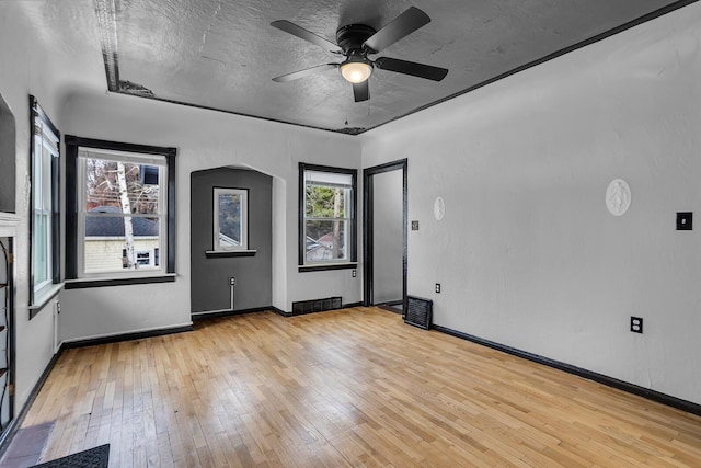 empty room with ceiling fan, light hardwood / wood-style floors, and a textured ceiling