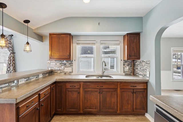 kitchen featuring lofted ceiling, sink, decorative light fixtures, stainless steel dishwasher, and kitchen peninsula