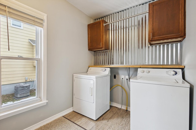 clothes washing area with cabinets, light hardwood / wood-style flooring, and washer and dryer