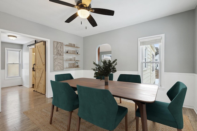 dining area featuring hardwood / wood-style floors, a barn door, a healthy amount of sunlight, and ceiling fan