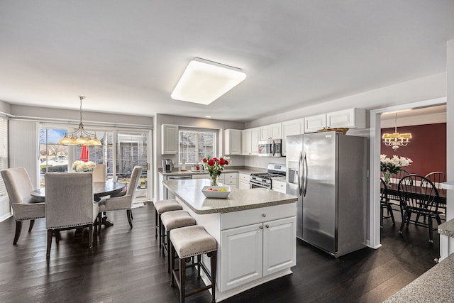 kitchen with appliances with stainless steel finishes, a center island, pendant lighting, and white cabinets