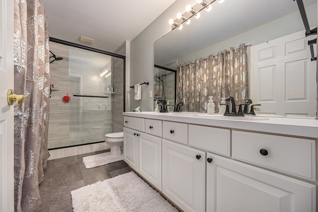 bathroom featuring double vanity, a stall shower, a sink, and toilet