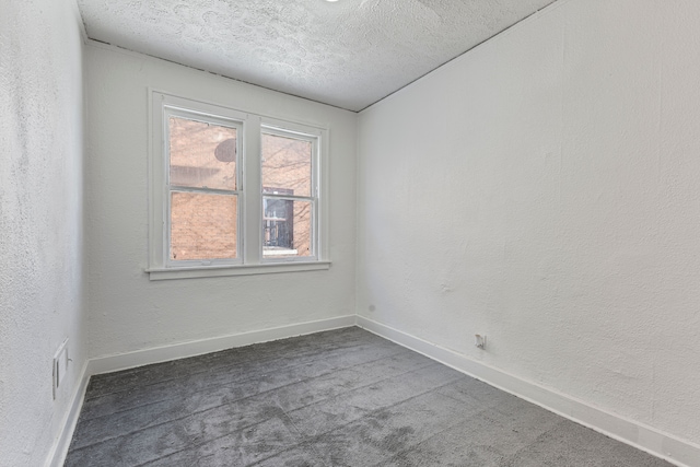 carpeted empty room featuring a textured ceiling