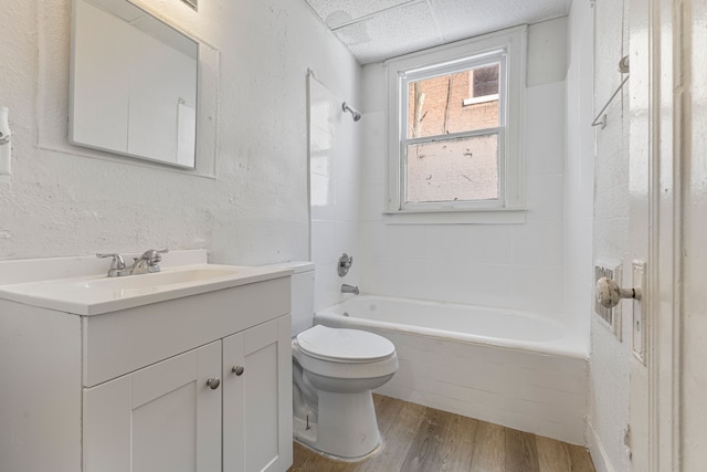 full bathroom with tiled shower / bath, hardwood / wood-style flooring, vanity, toilet, and a drop ceiling