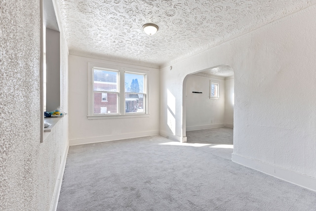 empty room featuring a textured ceiling, carpet floors, and a healthy amount of sunlight