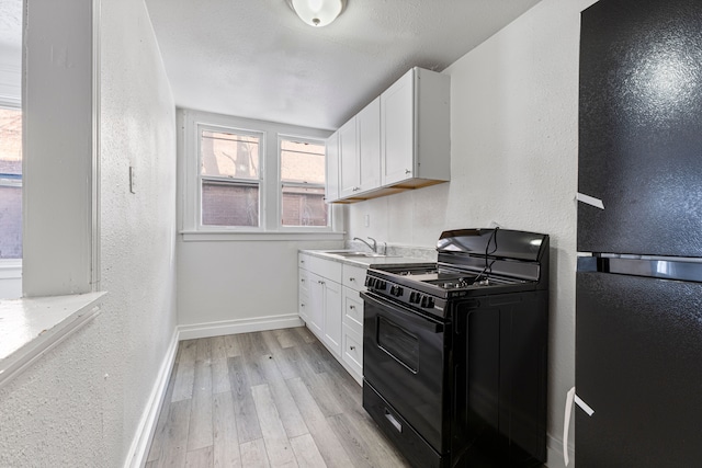 kitchen featuring white cabinetry, sink, black appliances, and light hardwood / wood-style floors