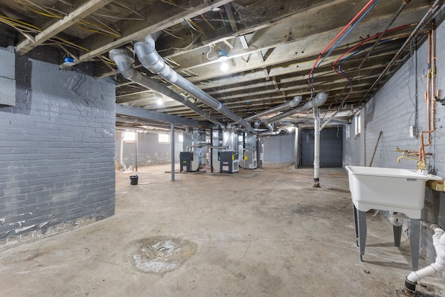 basement featuring brick wall, sink, and heating unit