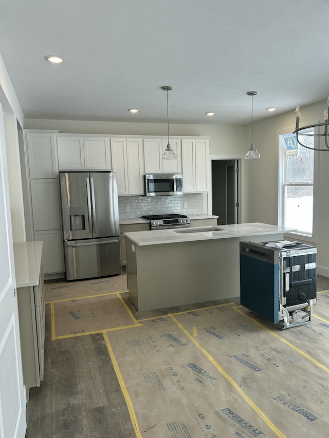 kitchen featuring hardwood / wood-style floors, appliances with stainless steel finishes, white cabinets, decorative backsplash, and pendant lighting