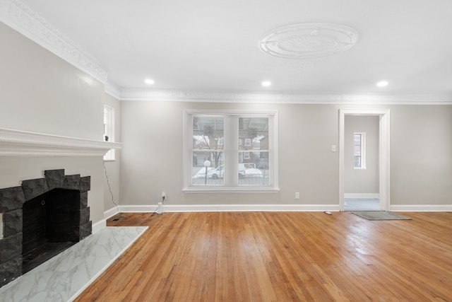 unfurnished living room featuring crown molding, a wealth of natural light, a fireplace, and light hardwood / wood-style flooring