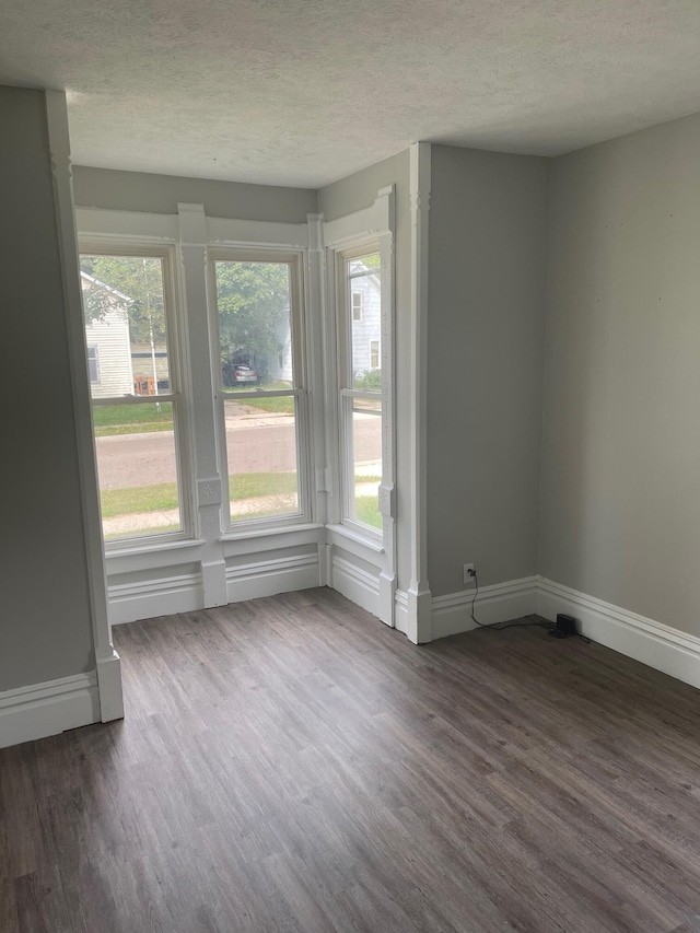 spare room with dark wood-type flooring and a textured ceiling