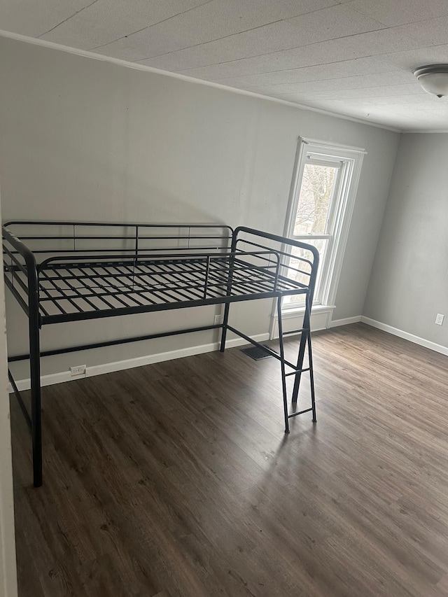 unfurnished bedroom with dark wood-type flooring and ornamental molding