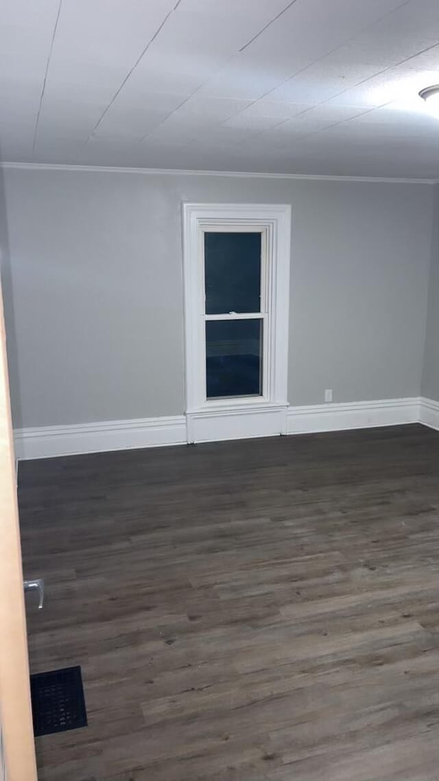 unfurnished room featuring ornamental molding and dark wood-type flooring