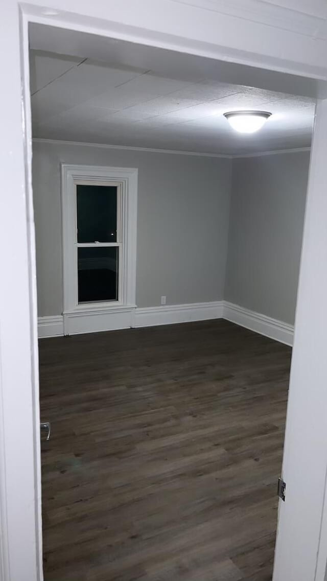 unfurnished room with dark wood-type flooring and ornamental molding