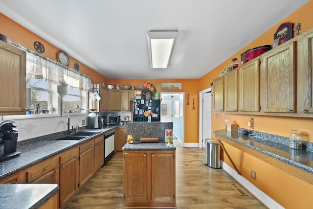 kitchen with a kitchen island, tasteful backsplash, sink, stainless steel appliances, and light hardwood / wood-style flooring