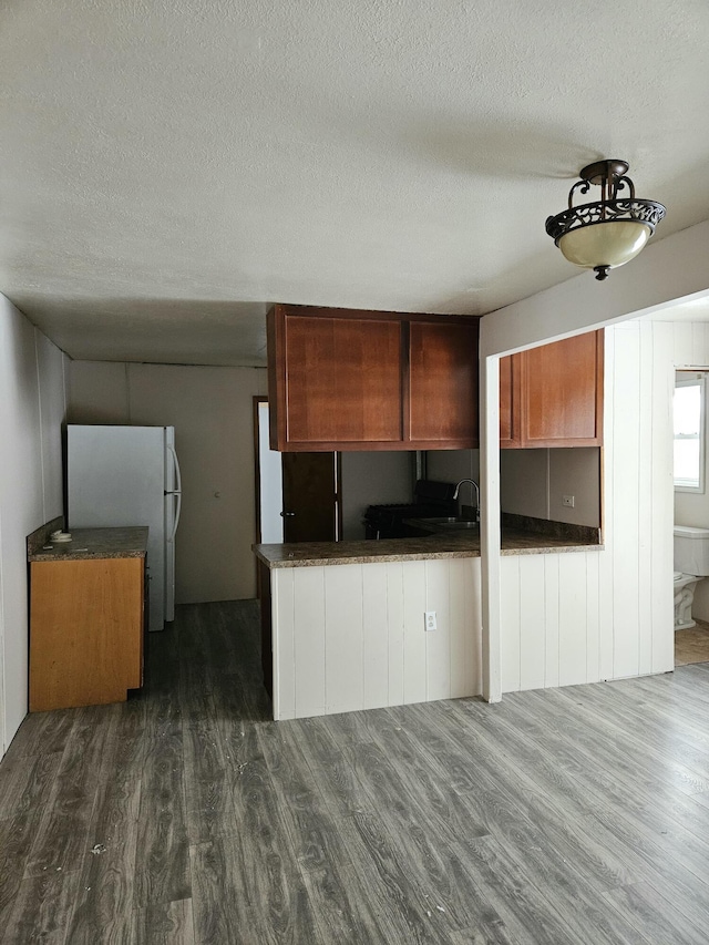 445 Colfax St, Cadillac, MI 49601 - kitchen with dark wood finished floors, a textured ceiling, freestanding refrigerator, dark countertops, and a sink