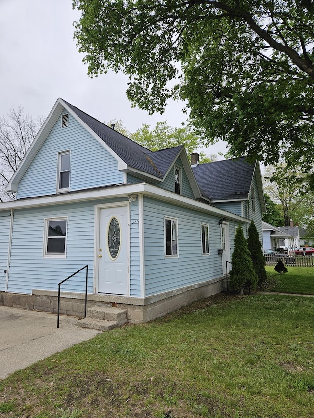 445 Colfax St, Cadillac, MI 49601 - traditional-style home featuring entry steps, a front yard, and roof with shingles