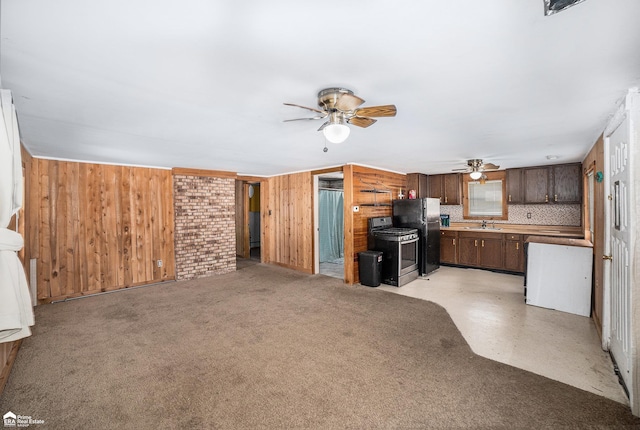 kitchen with wood walls, sink, stove, ceiling fan, and black fridge