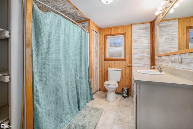 bathroom with vanity, toilet, and wood walls