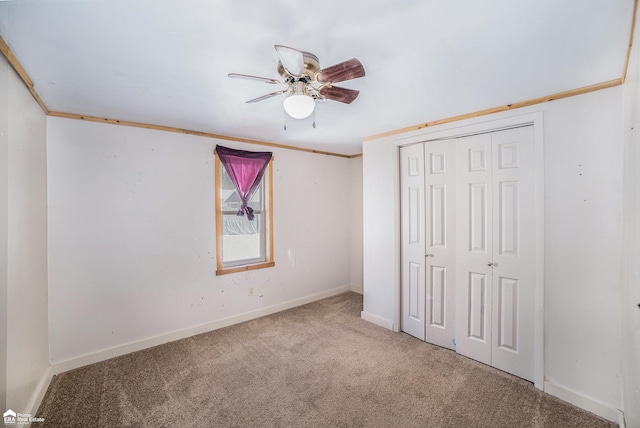 unfurnished bedroom with crown molding, carpet, ceiling fan, and a closet