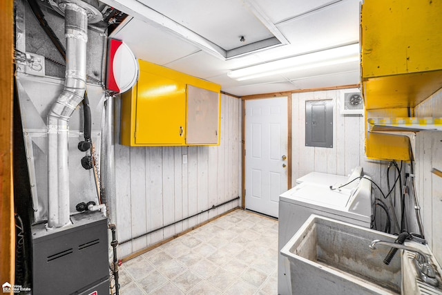 laundry room featuring washing machine and dryer, sink, electric panel, and wood walls