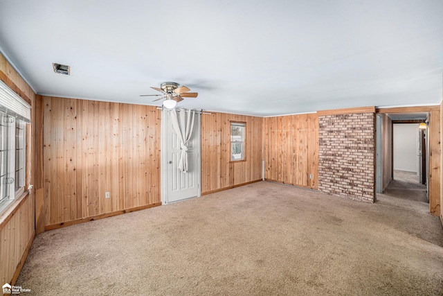 carpeted empty room with ceiling fan and wooden walls