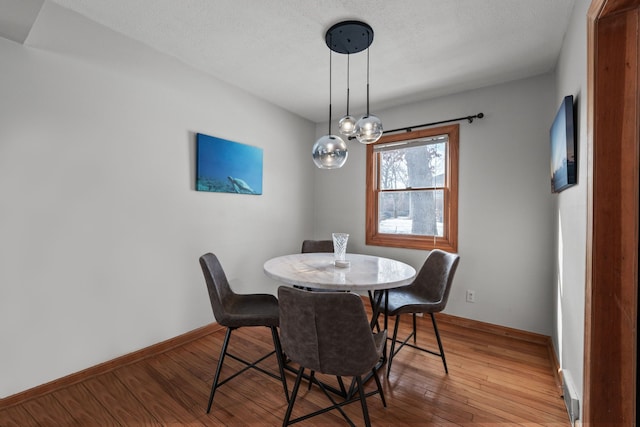 dining area with wood-type flooring and a textured ceiling