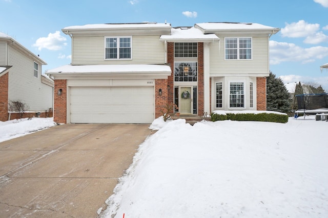 traditional-style home featuring a garage, concrete driveway, brick siding, and a trampoline